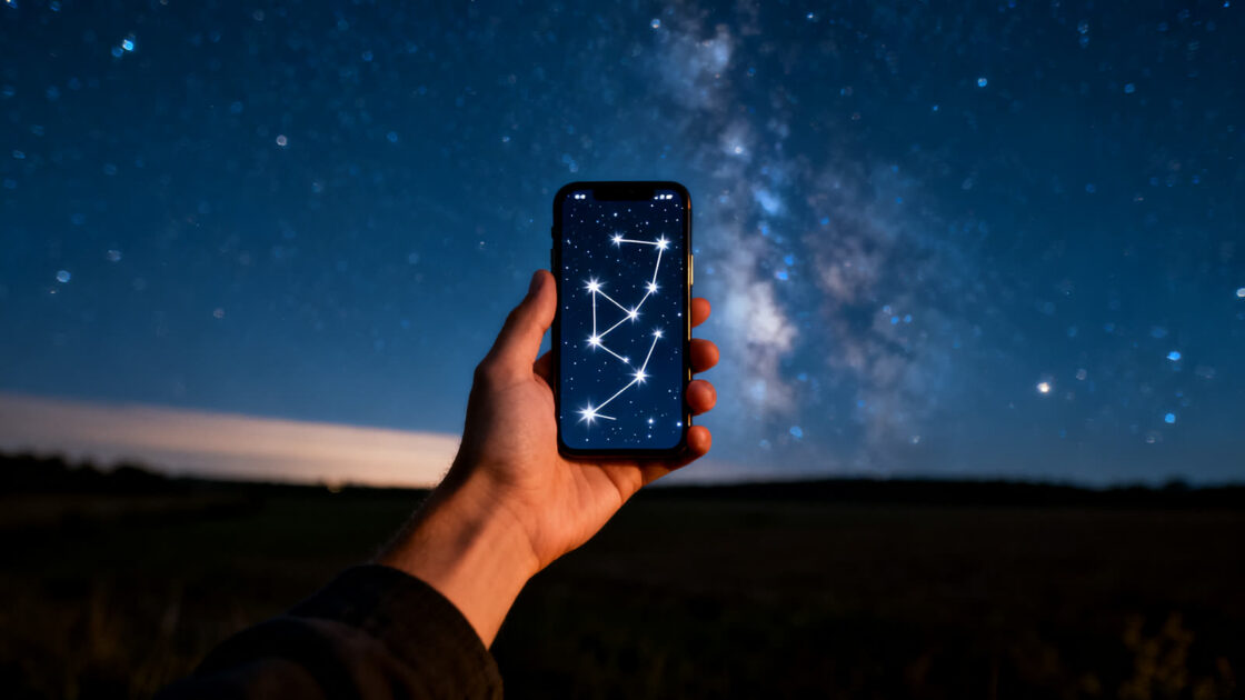Celular apontado para o céu estrelado mostrando constelações na tela