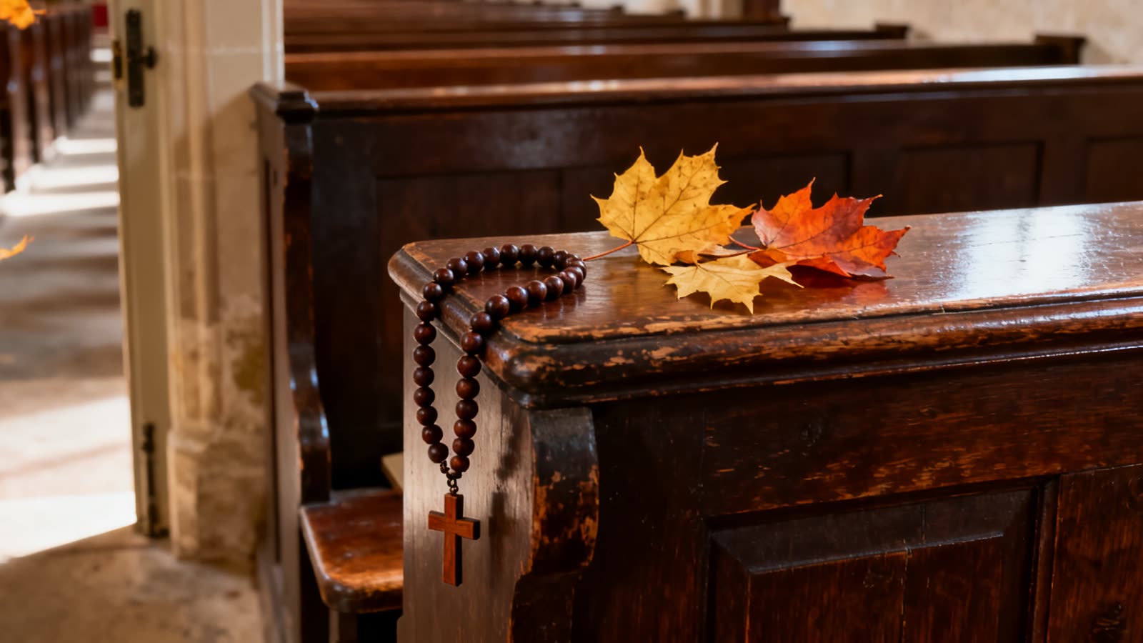 Un rosario de madera y hojas de otoño sobre el banco vacío de una iglesia antigua